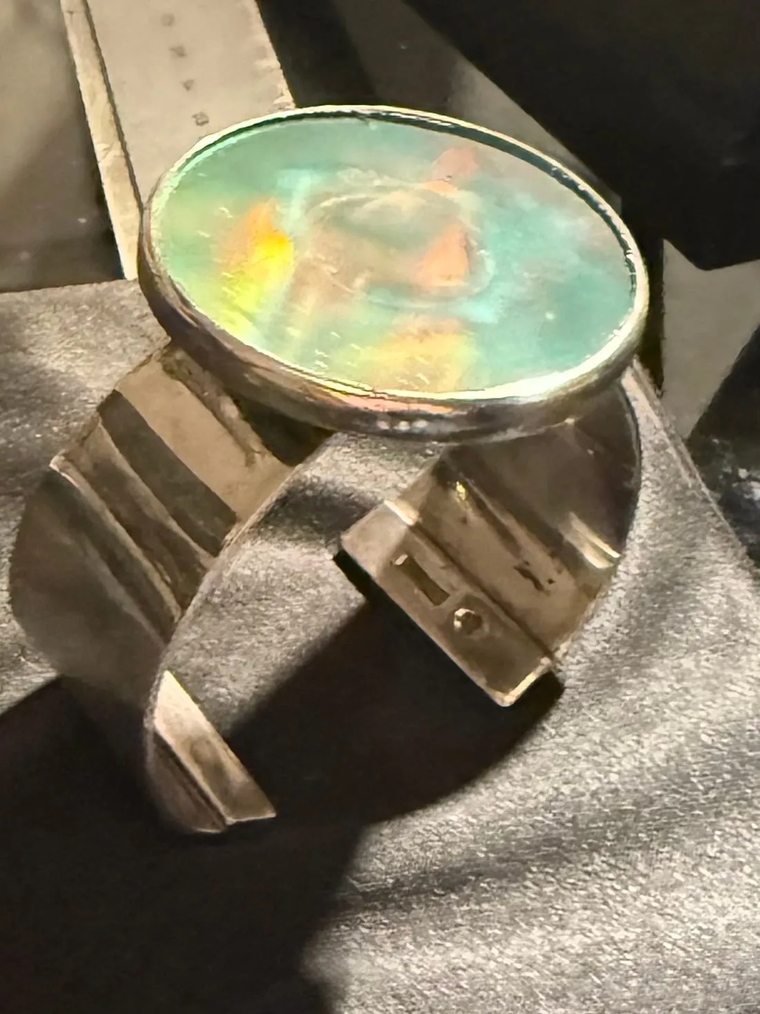 A silver cuff bracelet set with an embedded hologram.