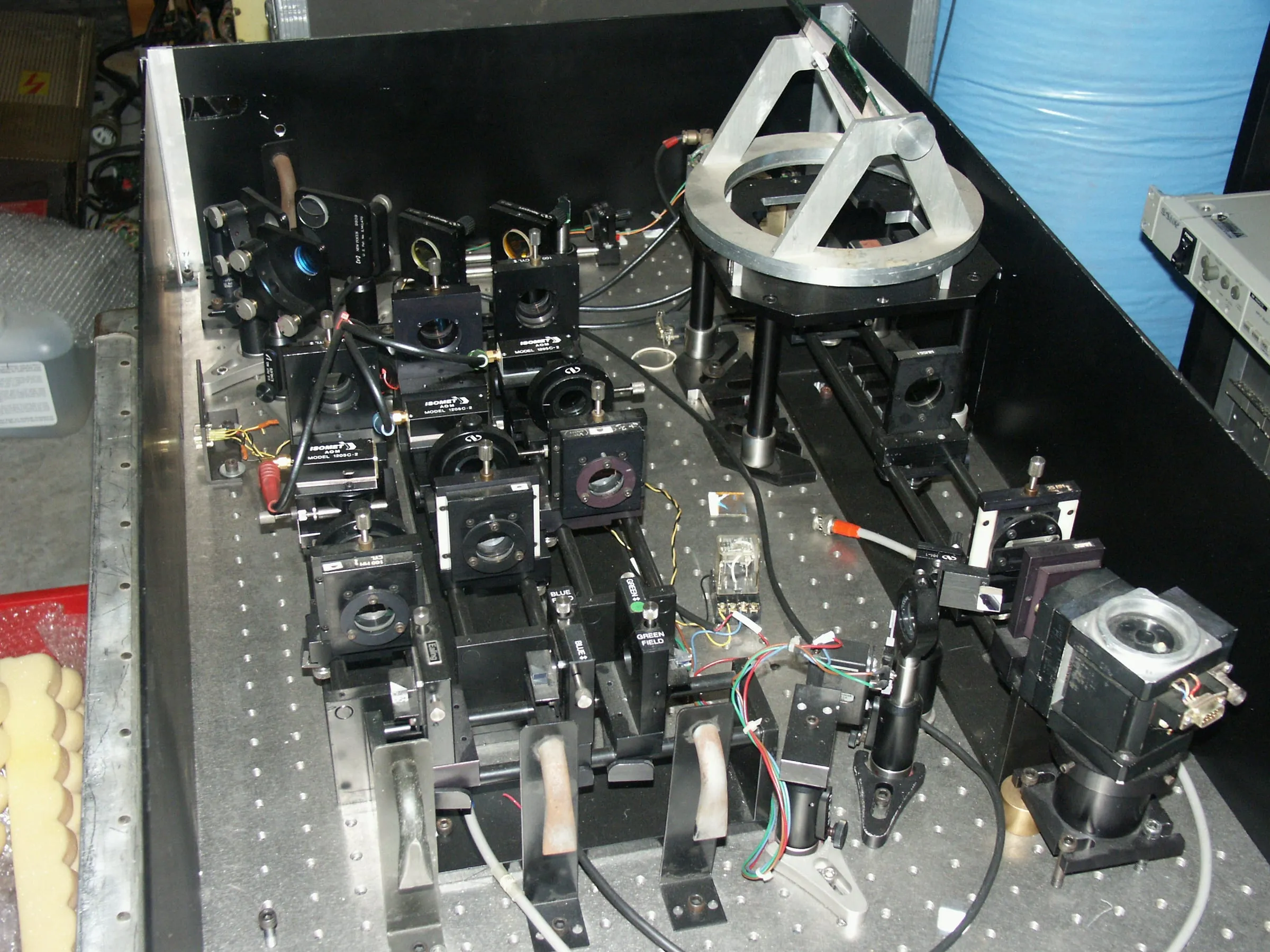 A dense optical bench of mirror mounts, lenses, and acousto-optic modulators from a laser projection system.